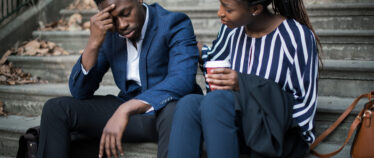 image of man and woman seated on cement stairs.