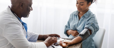 Male medical worker measuring blood presure of pregnant patient.